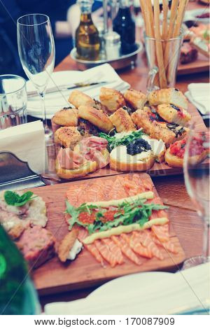 Restaurant table full of Italian starters, toned image