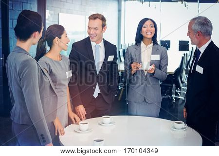 Businesspeople having tea and interacting during breaktime in office