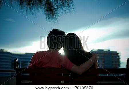 Happy sweethearts sit together  see the sunset