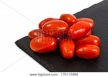 Small red oblong tomatoes on plate. Studio Photo