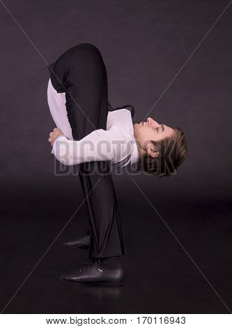Extraordinary gymnast on a black background. The man with no bones. Studio photography of circus performers..