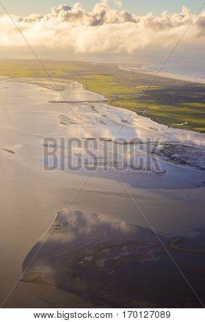 aerial sunset view of the mudflat coastline at low tide with water winding in the mud and sand bank Frisian island Ameland The Netherlands