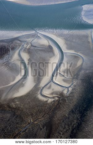 aerial view of the mudflat coastline at low tide with water winding in the mud and sand bank Frisian island Ameland The Netherlands