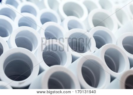 Plactic Plumbing connection fittings for plastic pipes. Orderly arranged in neat rows. Abstract industrial background.