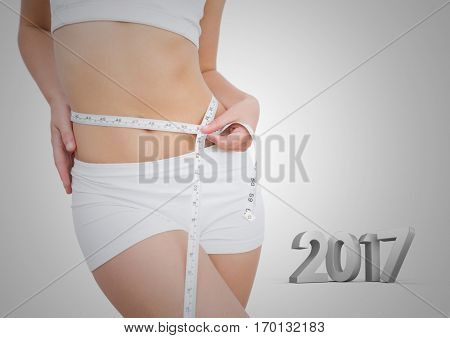 Mid section of woman measuring her waist against 3D 2017
