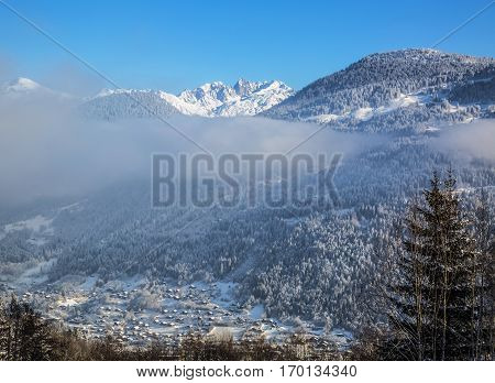 Chain of peaks in Alps above the clouds and villages
