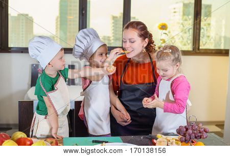 Three cute kids are preparing a fruit salad in the kitchen. Healthy eating