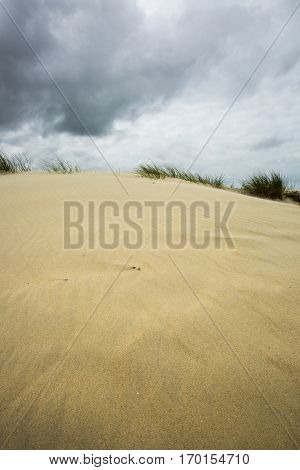 view on a sandy dune with cloudy dramatic sky