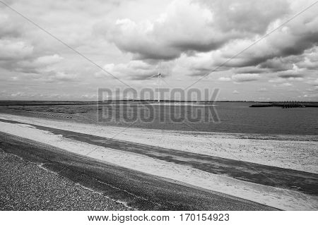 Black and white seaside view with power windmills, a dike and dramatic sky, Haringvliet, The Netherlands