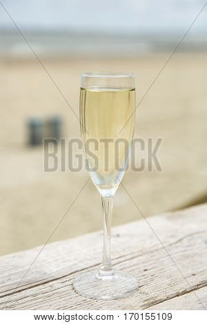 Champagne glass on a wooden table with beach background