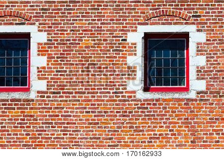Windows of traditional medieval house exterior on red brick wall background