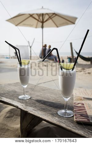 Cocktail glass with two straws and with beach landscape background