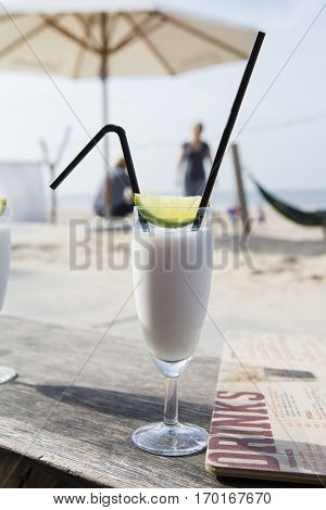 Cocktail glass with two straws and with beach landscape background
