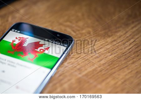 Smartphone On Wooden Background With 5G Network Sign 25 Per Cent Charge And Wales Flag On The Screen