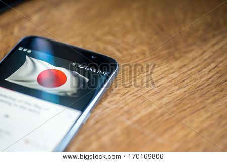 Smartphone On Wooden Background With 5G Network Sign 25 Per Cent Charge And Japan Flag On The Screen
