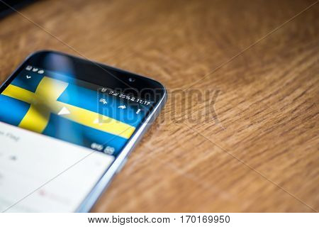 Smartphone On Wooden Background With 5G Network Sign 25 Per Cent Charge And Sweden Flag On The Scree