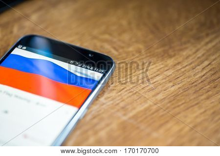 Smartphone On Wooden Background With 5G Network Sign 25 Per Cent Charge And Russia Flag On The Scree