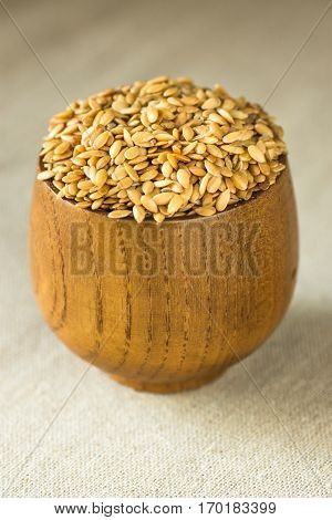 Flax seeds in a wood bowl on linen cloth, close up