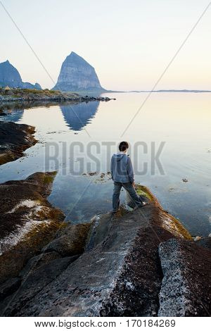 Norwegian landscape in the midnight sun with a man looking at the sea