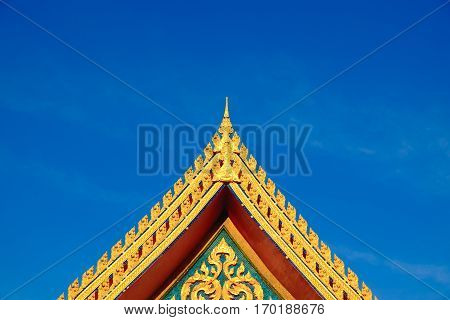 Gold color roof of buddhist temple with blue sky background. isosceles triangle shape.
