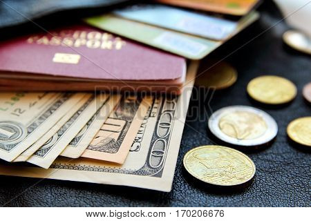 credit cards passport money peeking out from the bag close-up view on black leather background.