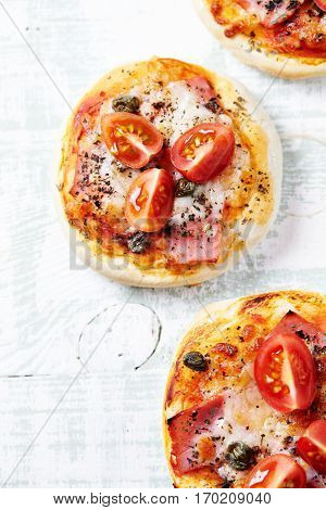Mini pizza topped with cherry tomatoes and capers