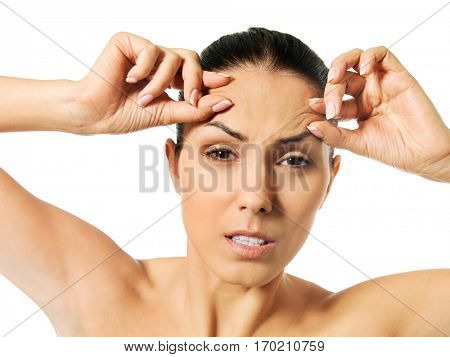 Worried young woman checking wrinkles on forehead