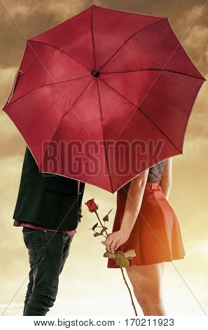 Girlfriend and boyfriend having a passionate kiss hidden behind the umbrella