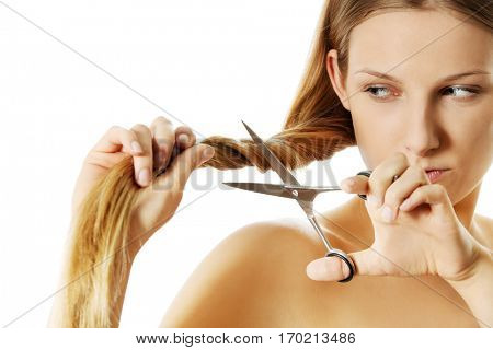 Attractive young woman is cutting her long natural hair