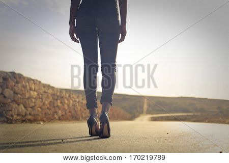 Black girl walking in high heels on endless coutry road