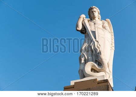 Old medieval of the Archangel Saint Michael fighting the dragon with a blue sky background and space for text
