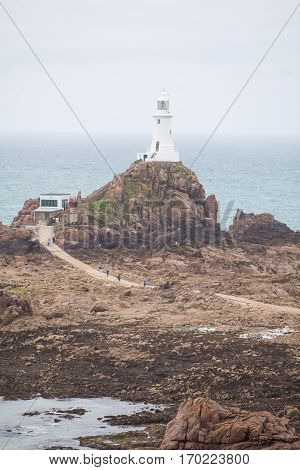 View of a lighthouse on Jersey island with unrecognizable people walking by.