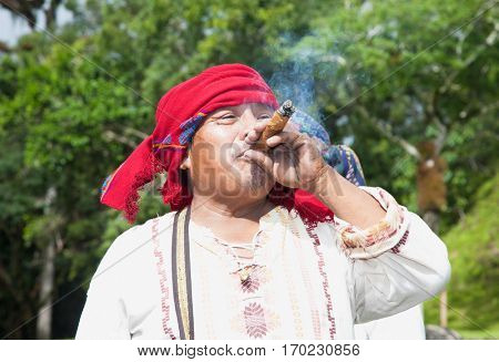 TIKAL, GUATEMALA - DEC 21, 2015: Unidentified Mayan smoking cigar on December 21, 2015  in Tikal, Guatemala. Traditional Mayan fire ceremony at the 2015 new year celebrations.