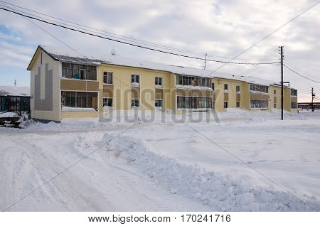 Old two-storied  yellow house in winter field with snow, North