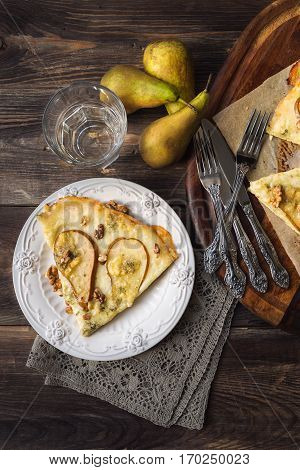 Homemade pizza with pear blue cheese mozzarella and wallnuts on rustic wooden background. Top view.
