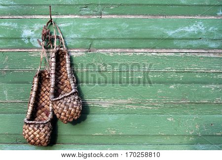 Old bast shoes (traditional russian footwear) on a green wooden background