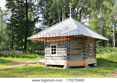 small wooden chapel with a metal roof in the forest