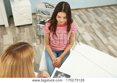 Doctor showing baby ultrasound image to pregnant woman