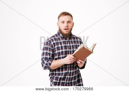 Surprised Bearded man in shirt holding book in hands in studio and looking at camera. Isolated white background
