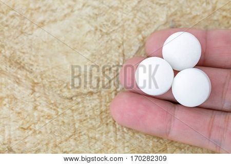 Top view of 3 white medicines on fingers with brown Mulberry paper copyspace