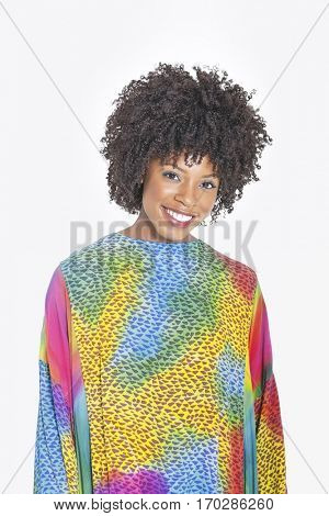 Portrait of an attractive African American woman in multicolored dashiki standing over gray background