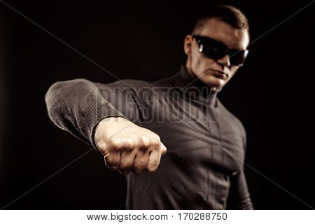 Right-hander punch. Close-up of a man's fist. Sunglasses. Studio shot.