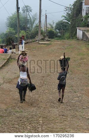 Sao Tome, Sao Tome and Principe - July 22, 2015: Unidentified people carrying firewood and fruits in a village