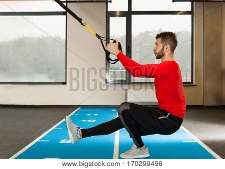 white curly bearded sporty man exercising with fitness straps in gym
