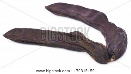 Closeup of Edible carob fruits over white background