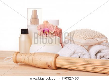 Spa still life on a wooden desk on a white background. Healthy lifestyle, body care, bathhouse, Spa treatment and relaxation concept. Bamboo massage stick, towel, moisturizing cream and other toiletry