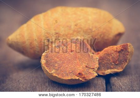 Whole with pieces of turmeric on wooden surface