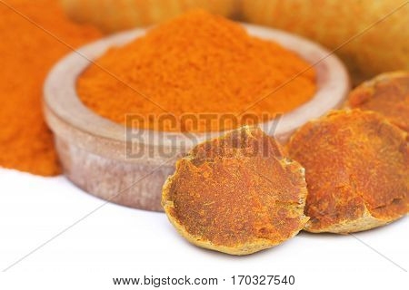 Whole and ground turmeric in bowl over white background