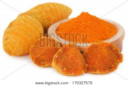 Whole and ground turmeric in bowl over white background