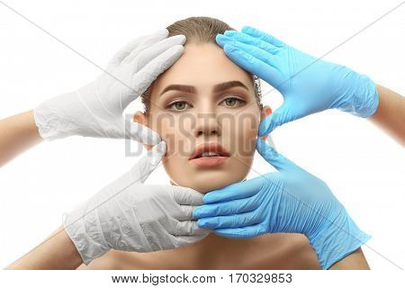 Hands touching female face on white background. Plastic surgery concept